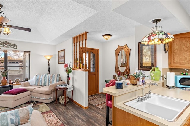 interior space with ceiling fan, sink, dark wood-type flooring, and a textured ceiling