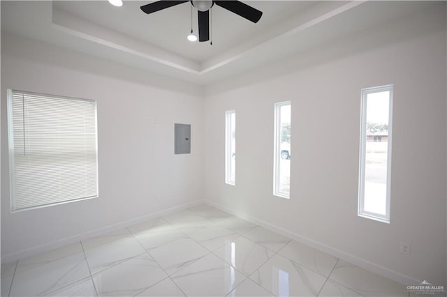 spare room featuring electric panel, baseboards, and a raised ceiling