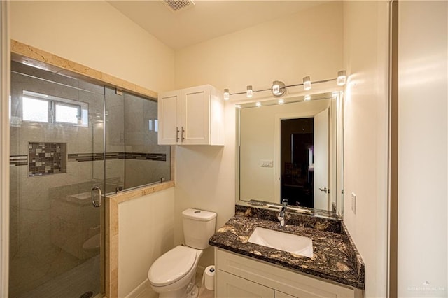 bathroom featuring vanity, toilet, and a shower with shower door