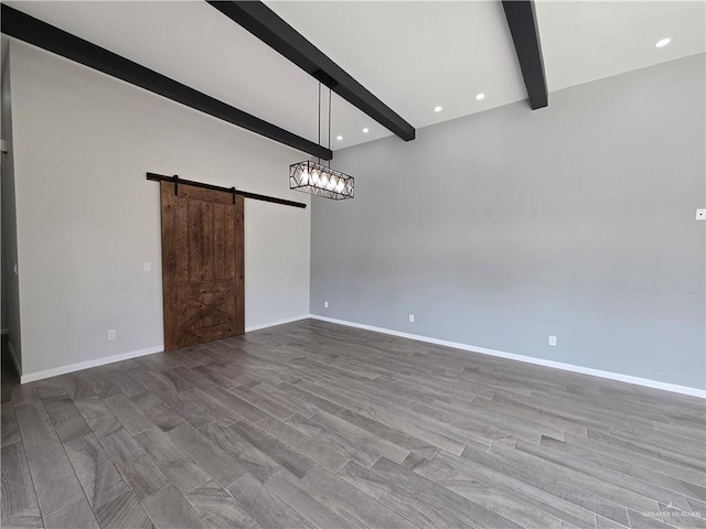 unfurnished room featuring beamed ceiling, a barn door, and hardwood / wood-style flooring