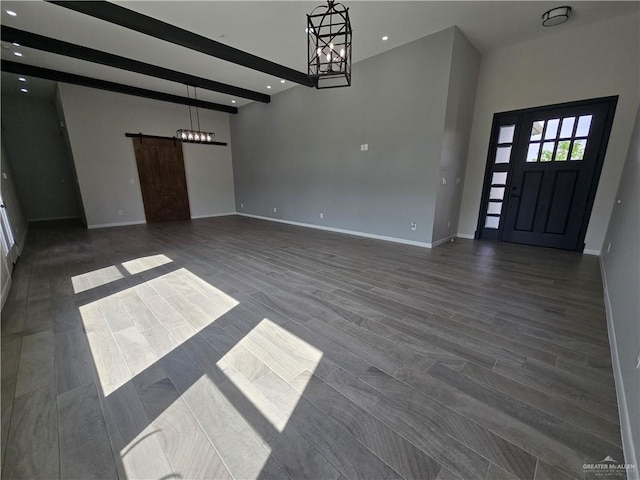 entrance foyer featuring beam ceiling, a barn door, dark hardwood / wood-style flooring, and a chandelier