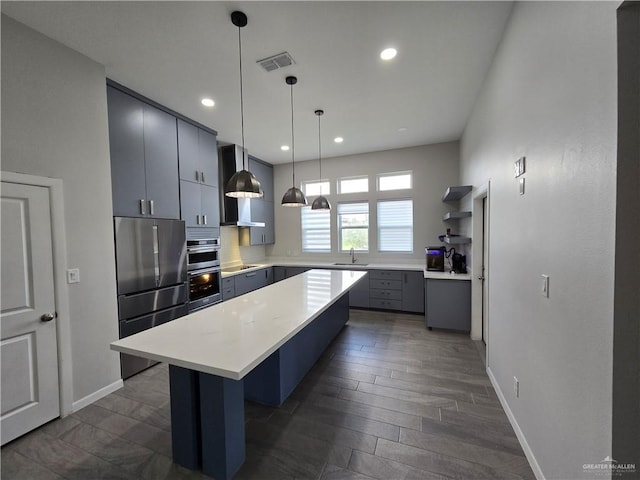 kitchen featuring a center island, sink, hanging light fixtures, stainless steel appliances, and dark hardwood / wood-style floors