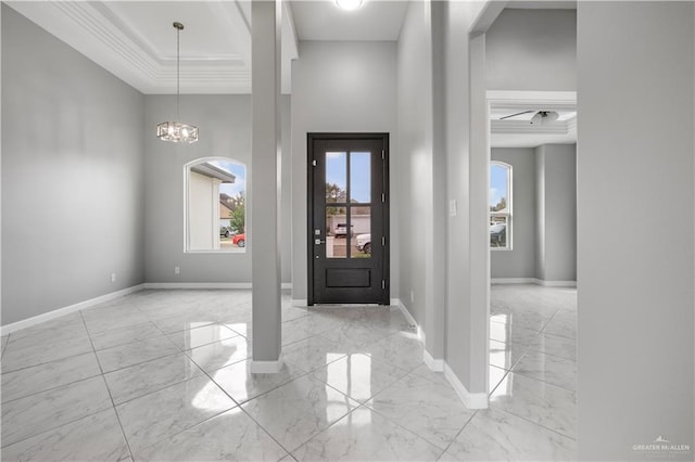 entrance foyer featuring a tray ceiling, crown molding, and a chandelier