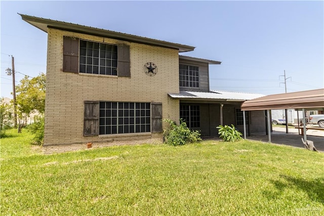 rear view of property with a carport and a yard