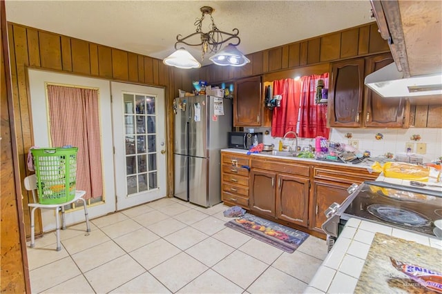 kitchen featuring sink, hanging light fixtures, tile countertops, stainless steel fridge, and range