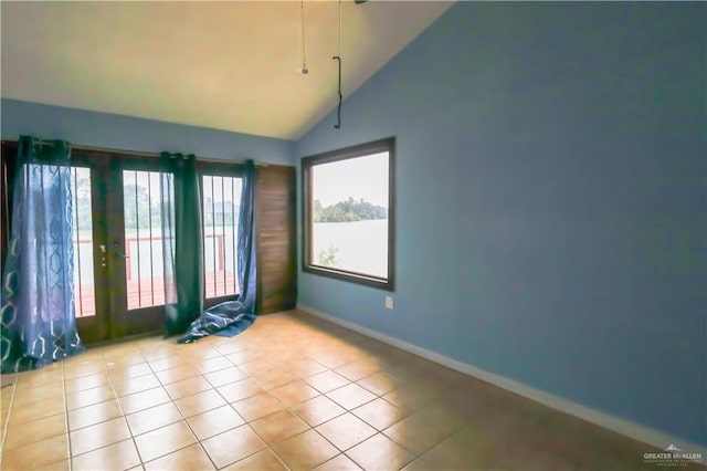 tiled empty room with french doors and high vaulted ceiling