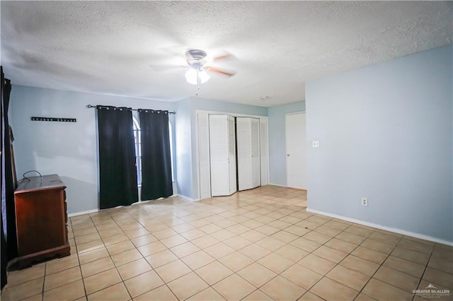 empty room with ceiling fan, light tile patterned floors, and a textured ceiling