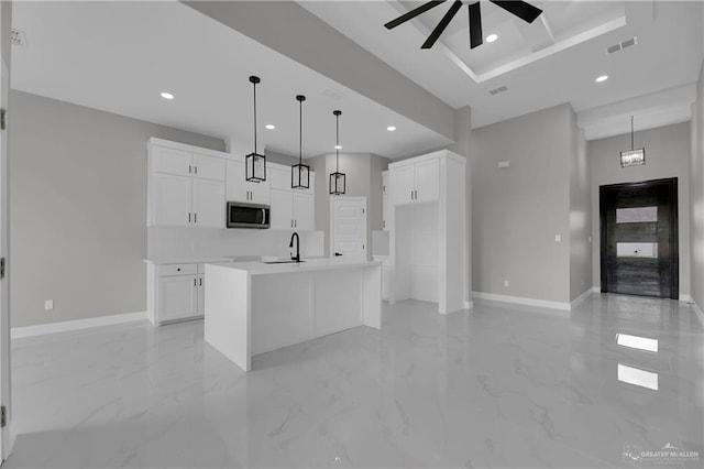 kitchen featuring a center island with sink, white cabinets, sink, hanging light fixtures, and ceiling fan