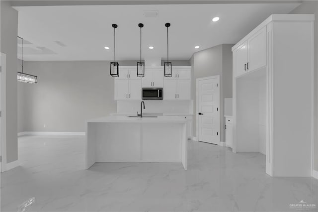 kitchen featuring white cabinetry, sink, an island with sink, and hanging light fixtures