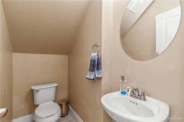 bathroom featuring toilet, sink, and vaulted ceiling