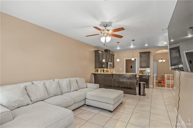 tiled living room with ceiling fan with notable chandelier