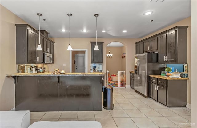 kitchen featuring a breakfast bar, appliances with stainless steel finishes, decorative light fixtures, light tile patterned flooring, and kitchen peninsula