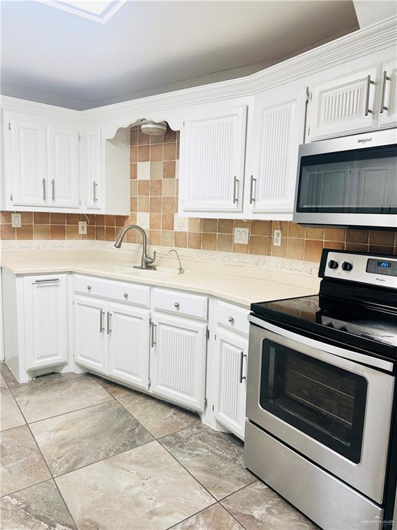 kitchen featuring white cabinetry, appliances with stainless steel finishes, sink, and backsplash