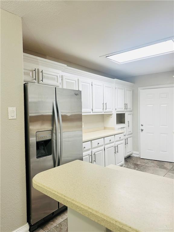 kitchen featuring white cabinetry and stainless steel fridge