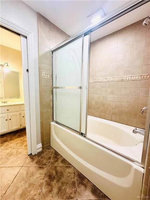 bathroom with enclosed tub / shower combo, tile patterned floors, and vanity