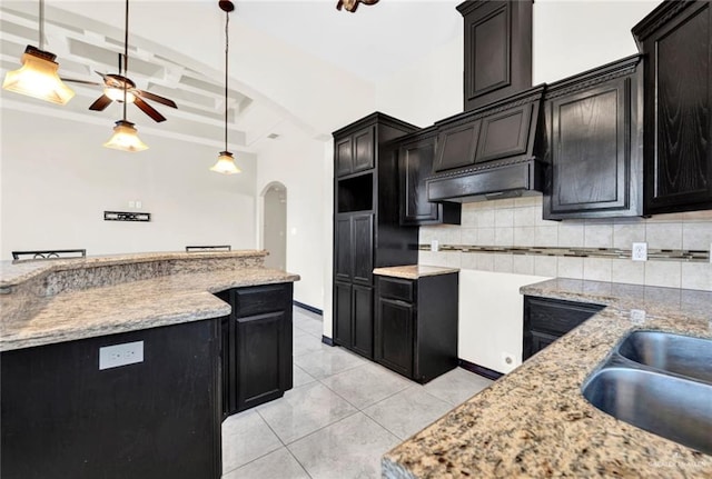 kitchen featuring sink, decorative backsplash, coffered ceiling, light tile patterned floors, and ceiling fan