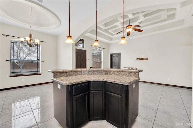 kitchen with light tile patterned flooring, a kitchen island, coffered ceiling, and decorative light fixtures