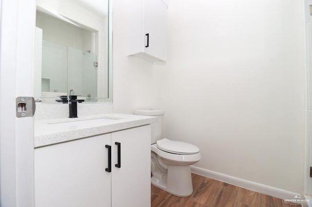 bathroom with vanity, toilet, wood-type flooring, and a shower with shower door