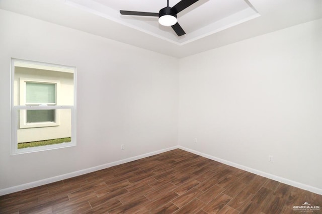 unfurnished room featuring dark hardwood / wood-style floors, ceiling fan, and a tray ceiling