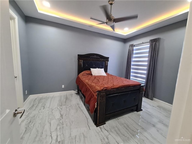 bedroom featuring marble finish floor, a ceiling fan, baseboards, and a raised ceiling
