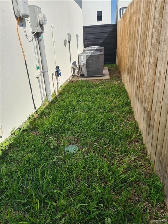 view of yard featuring central air condition unit and fence