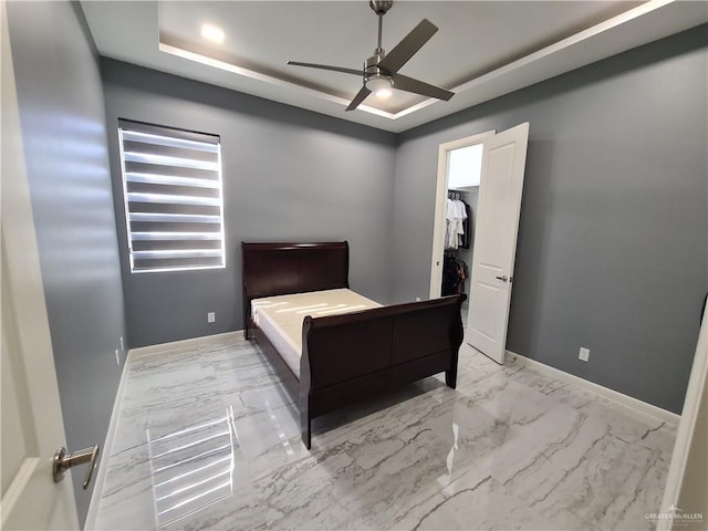 bedroom featuring baseboards, marble finish floor, and a raised ceiling