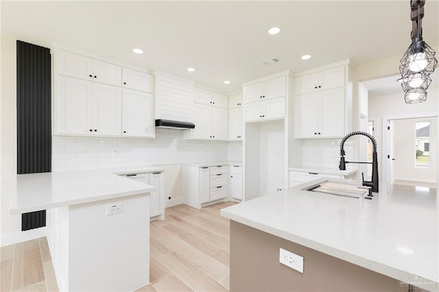 1027 Broken Arrow Dr, Alamo, TX 78516 - kitchen with a peninsula, a sink, decorative backsplash, white cabinetry, and a kitchen breakfast bar