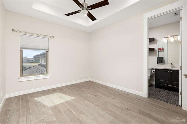 8101 N 5th St, Mcallen, TX 78504 - unfurnished bedroom with baseboards, ensuite bath, a tray ceiling, light wood-type flooring, and a sink