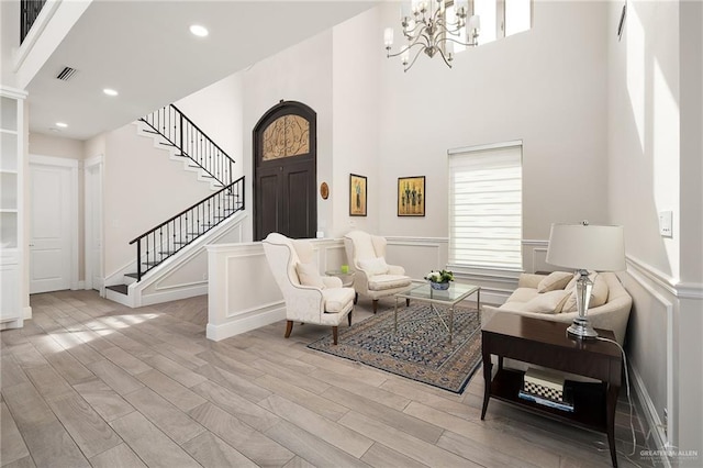 interior space with light wood-style flooring, stairs, visible vents, and a decorative wall