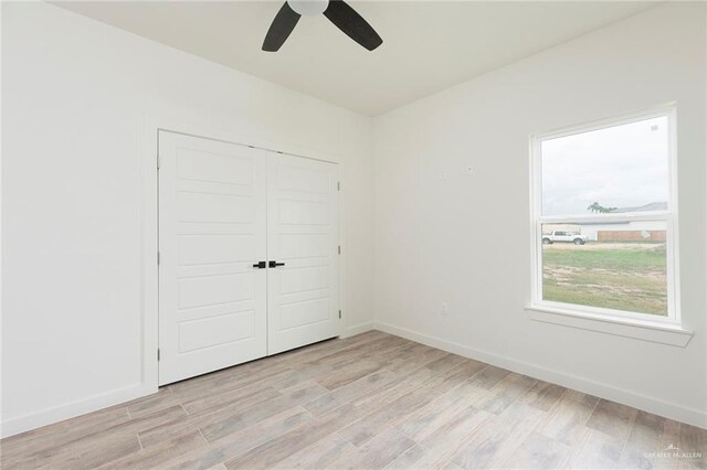 unfurnished bedroom with light wood-type flooring, a closet, and ceiling fan