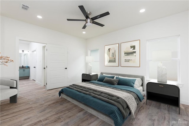 bedroom featuring ensuite bathroom, light hardwood / wood-style flooring, and ceiling fan