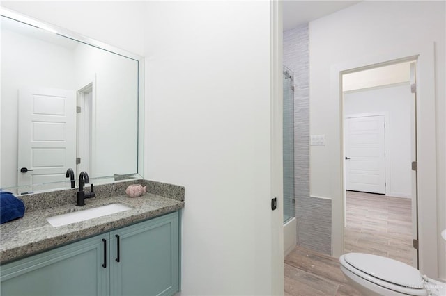 full bathroom with vanity, shower / bath combination with glass door, toilet, and wood-type flooring