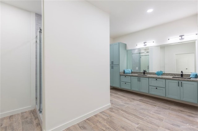 bathroom featuring hardwood / wood-style floors, vanity, and a shower with shower door