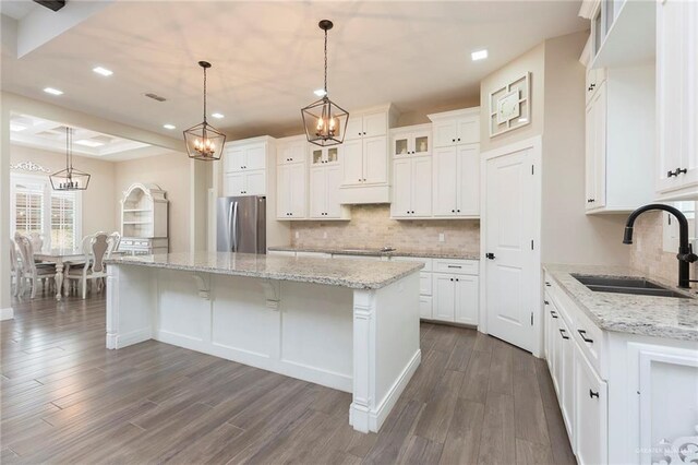 kitchen featuring dark hardwood / wood-style flooring, sink, a center island, white cabinetry, and stainless steel refrigerator