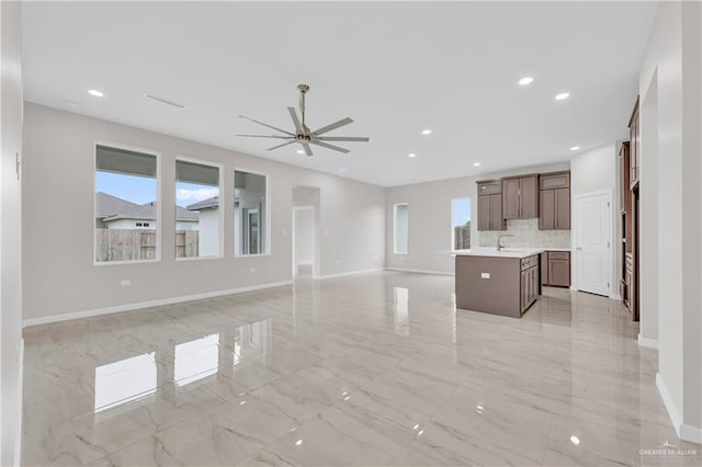 unfurnished living room featuring marble finish floor, baseboards, ceiling fan, recessed lighting, and a sink