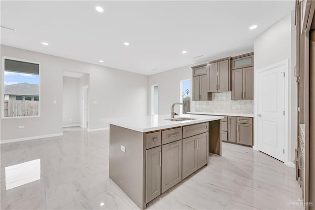 kitchen with marble finish floor, a kitchen island with sink, recessed lighting, tasteful backsplash, and a sink