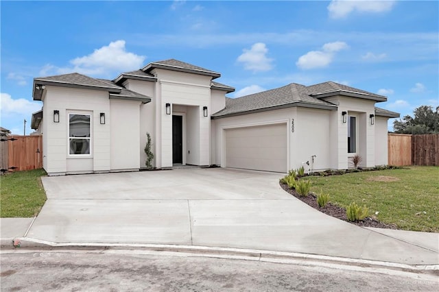 prairie-style home featuring a garage, a front lawn, fence, and concrete driveway
