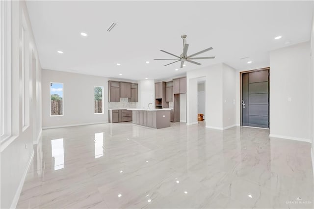 unfurnished living room with baseboards, a ceiling fan, recessed lighting, and marble finish floor
