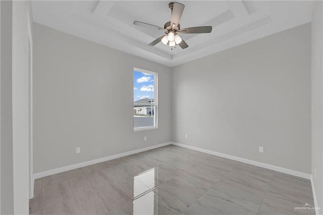 unfurnished room with baseboards, a ceiling fan, and a raised ceiling