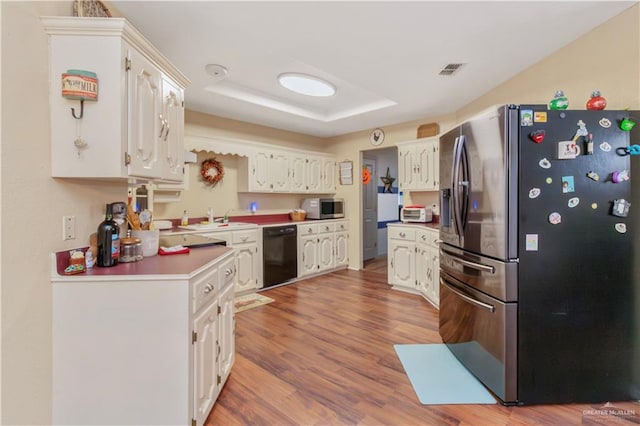 kitchen featuring white cabinets, stainless steel appliances, a tray ceiling, and hardwood / wood-style floors