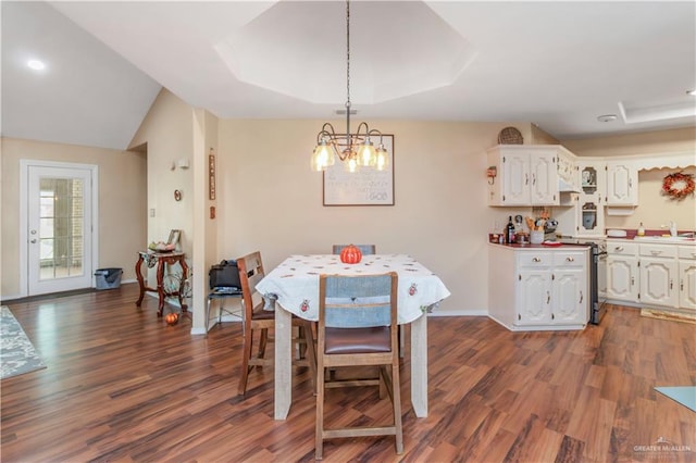 dining space featuring a tray ceiling, dark hardwood / wood-style flooring, and a notable chandelier