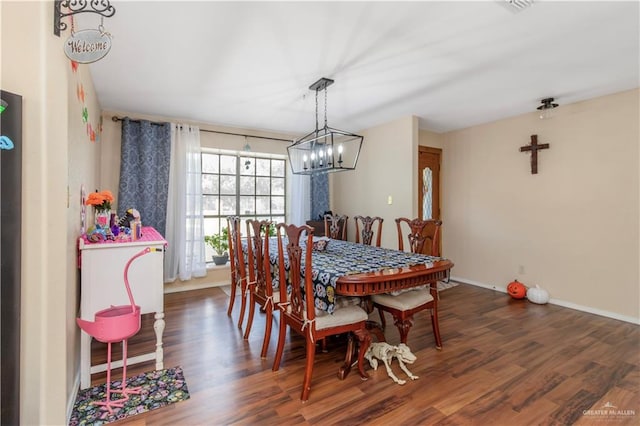 dining space with dark hardwood / wood-style floors and an inviting chandelier