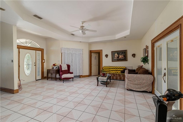 living room with ceiling fan, french doors, light tile patterned floors, and a tray ceiling