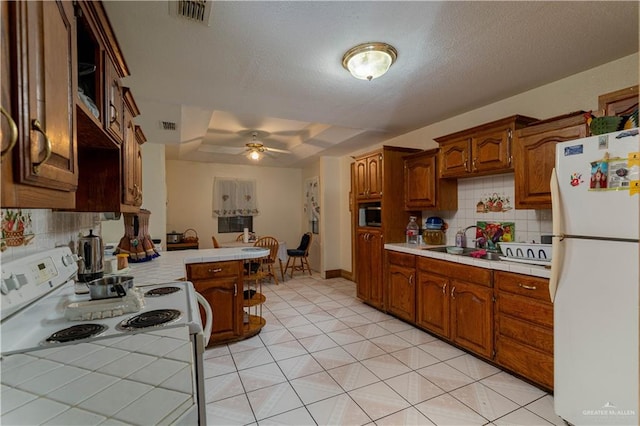 kitchen with kitchen peninsula, backsplash, white appliances, ceiling fan, and sink