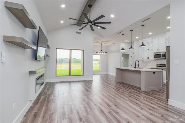 2316 Piedra St, Edinburg, TX 78542 - unfurnished living room with a glass covered fireplace, a ceiling fan, beamed ceiling, light wood finished floors, and a sink