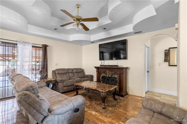 living room with ceiling fan and a tray ceiling