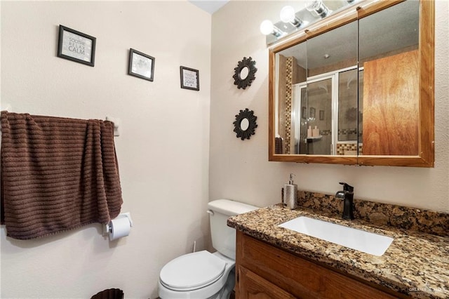 bathroom featuring vanity, a shower with shower door, and toilet