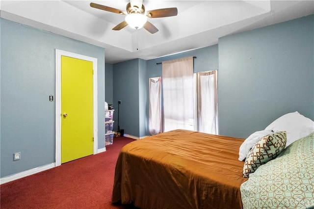 carpeted bedroom featuring a tray ceiling and ceiling fan