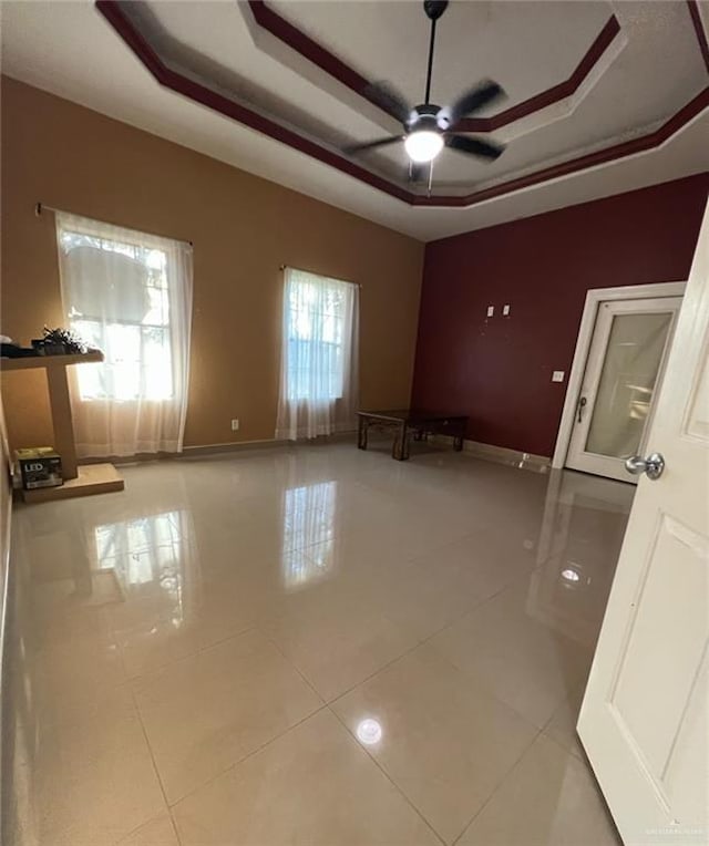 empty room featuring a raised ceiling, tile patterned floors, and a healthy amount of sunlight