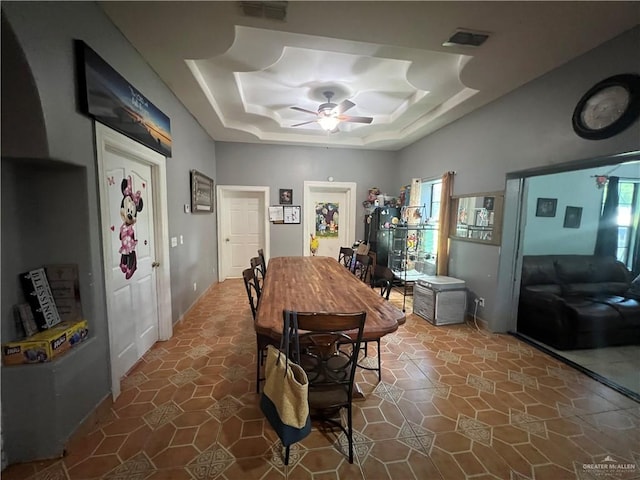 dining space with a tray ceiling, ceiling fan, and a healthy amount of sunlight